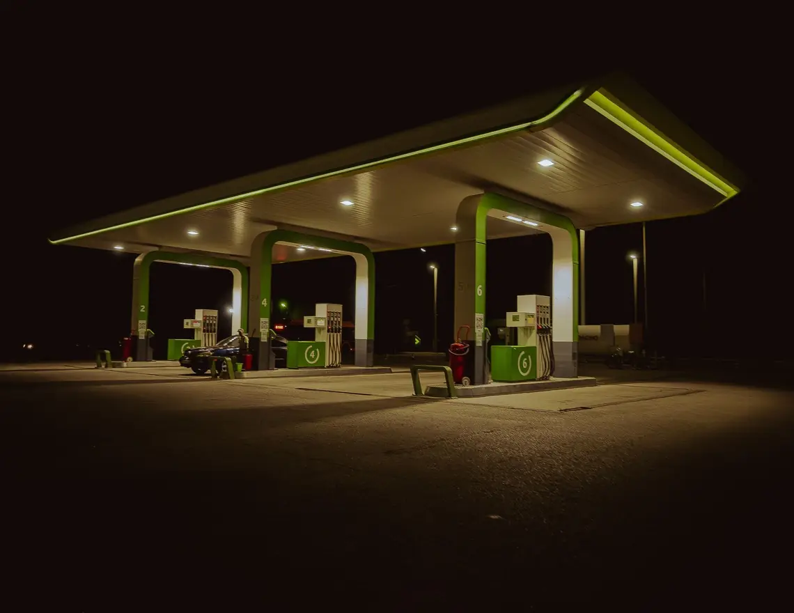 Estación de servicio iluminada de noche, con sus dispensarios bajo la techumbre